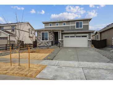 Charming two-story home with gray siding, stone accents, and a well-maintained front yard at 9692 Cathay St, Commerce City, CO 80022
