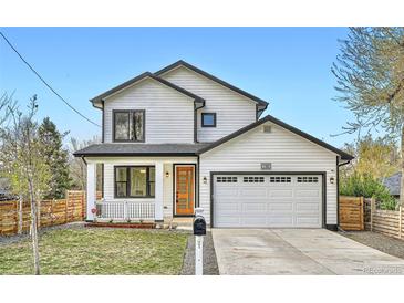 Charming two-story home with white siding, black trim, covered porch, and attached two-car garage at 11885 W Katherine Ave, Lakewood, CO 80401