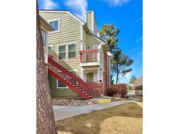 Two-story condo featuring a red stairwell, brick facade, and a quaint balcony, all bathed in bright daylight at 912 S Dearborn Way # 3, Aurora, CO 80012