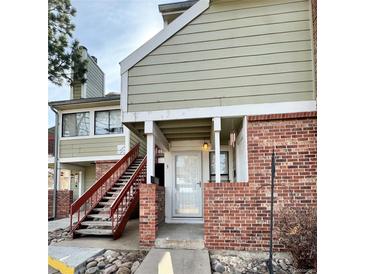 Charming condo entrance features brick accents, covered porch, and stairway to the upper level at 912 S Dearborn Way # 3, Aurora, CO 80012