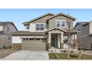 Two-story house with gray siding, stone accents, and a two-car garage at 4823 Astor Pl, Brighton, CO 80601