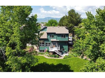 Lovely two-story home with a well-maintained lawn, mature trees, and a deck, creating a serene backyard retreat at 8296 S Reed St, Littleton, CO 80128