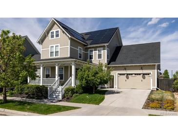 Charming two-story home with a covered porch, well-maintained lawn, and solar panels on the roof at 6072 Chester St, Denver, CO 80238