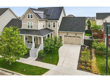 Inviting two-story home featuring a welcoming front porch and solar panels on the roof at 6072 Chester St, Denver, CO 80238