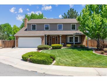 Charming two-story home with a brick facade, manicured lawn, and attached two-car garage at 7312 S Moore Ct, Littleton, CO 80127