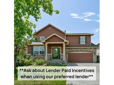 Charming two-story home featuring wood siding, stone accents, and a well-maintained front lawn and attached two-car garage at 9919 Memphis St, Commerce City, CO 80022
