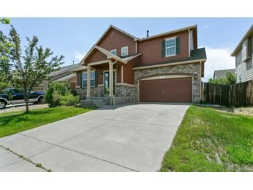 Charming two-story home with stone accents, a well-manicured lawn, and a spacious driveway at 9919 Memphis St, Commerce City, CO 80022