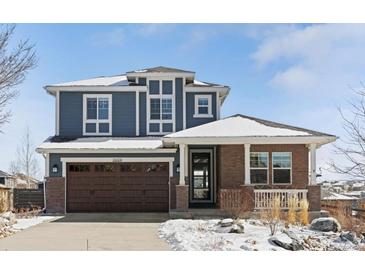 Charming two-story home featuring blue siding, brick accents, a two-car garage and snow covered yard at 26531 E Calhoun Pl, Aurora, CO 80016