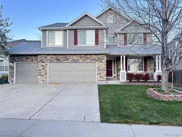 Charming two-story home with stone accents, gray siding, landscaped yard and a three car attached garage at 5724 S Rome St, Aurora, CO 80015