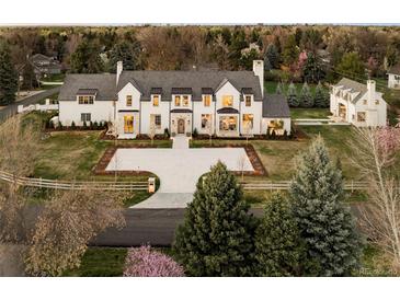 Stunning white home with a large yard and a circular driveway, surrounded by lush trees and landscaping at 20 Viking Dr, Cherry Hills Village, CO 80113