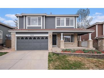 Charming two-story home with a gray exterior, brick accents, landscaped front yard, and attached two-car garage at 9250 Roadrunner Dr, Highlands Ranch, CO 80129