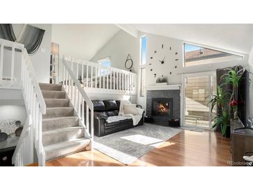 Bright living room with hardwood floors, fireplace, and adjacent loft area for relaxing or entertaining at 972 S Zeno Way, Aurora, CO 80017