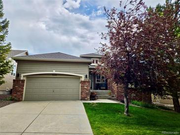 Charming single-Gathering home features a two-car garage, brick accents, and a well-manicured front lawn at 1033 Bramblewood Dr, Castle Pines, CO 80108