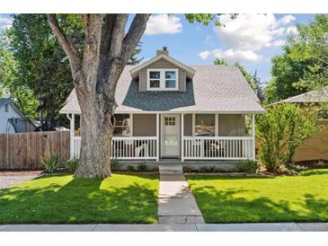 Charming home featuring a cozy front porch, well-manicured lawn, and a large tree providing shade at 3976 S Washington St, Englewood, CO 80113