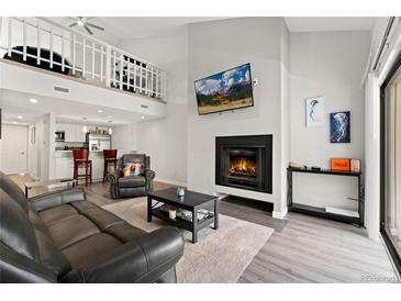 Spacious living room features a fireplace, vaulted ceiling, and loft overlooking a modern open kitchen at 1160 S Monaco Pkwy # 6, Denver, CO 80224