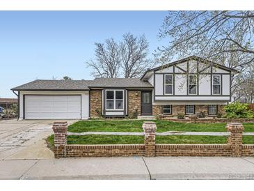 Charming home with a well-manicured lawn, brick accents, and a two-car garage on a sunny day at 10020 Bryant St, Denver, CO 80260