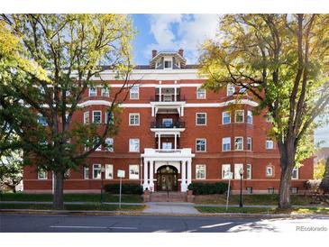Three-story red brick condo building with mature trees, white trim, and inviting entrance at 836 E 17Th Ave # 2B, Denver, CO 80218