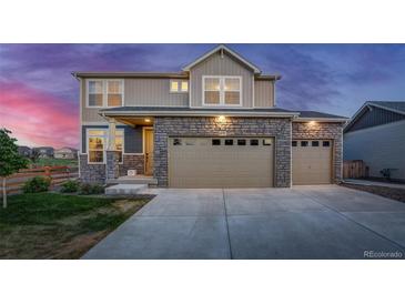 Two-story house with stone and beige siding, two-car garage, and landscaping at 16198 E 111Th Pl, Commerce City, CO 80022