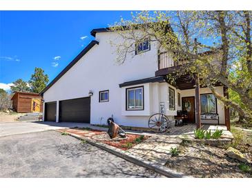 Charming home exterior boasts a two-car garage and a welcoming front porch with rustic decor at 1673 Woodmoor Dr, Monument, CO 80132