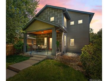 Inviting two-story home featuring a covered front porch and manicured lawn at dusk at 3770 Osceola St, Denver, CO 80212