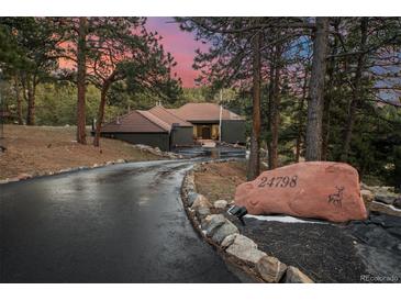 Beautiful exterior of home featuring a long driveway and mature trees at 24798 Foothills N Dr, Golden, CO 80401