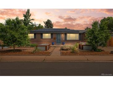 Charming brick home featuring a landscaped front yard, solar panels, and blue door at 5455 E Iowa Ave, Denver, CO 80222