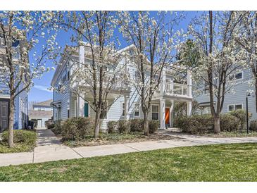Charming two-story home with light blue siding and a welcoming front porch and blossoming trees at 7453 E 26Th Ave # 2, Denver, CO 80238