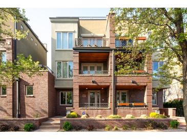 Charming multi-story townhome with red brick facade, multiple balconies, and well-kept front landscaping at 907 E 22Nd Ave, Denver, CO 80205
