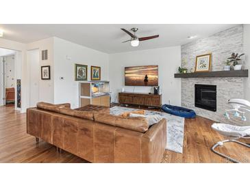 Cozy living room with fireplace, ceiling fan, wood floors, and exposed brick at 24356 E Powers Ave, Aurora, CO 80016
