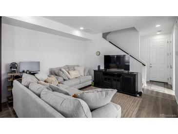 Bright living room with a large sectional sofa, television, and modern decor at 18199 E 96Th Ave, Commerce City, CO 80022