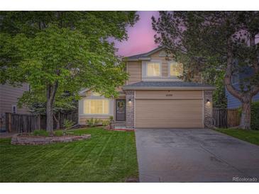 Charming two-story home with a well-manicured lawn, lush trees, and a welcoming two-car garage at 16200 Hedgeway Dr, Parker, CO 80134