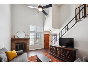 Inviting living room featuring a fireplace, a high ceiling with a ceiling fan, and a staircase at 7705 W 87Th Dr, Arvada, CO 80005