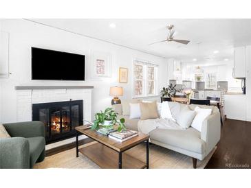 Open-concept living room with a fireplace, neutral decor, and seamless flow to the kitchen at 3139 Chase St, Wheat Ridge, CO 80214