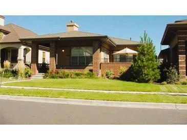 Charming brick home features a manicured front lawn and inviting front porch at 1076 Rosemary St, Denver, CO 80230