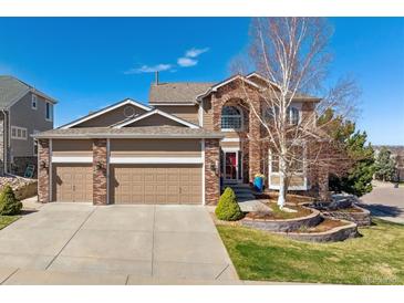 Charming front exterior featuring a brick facade, well-manicured lawn, and a three-car garage at 1863 Rose Petal Ct, Castle Rock, CO 80109
