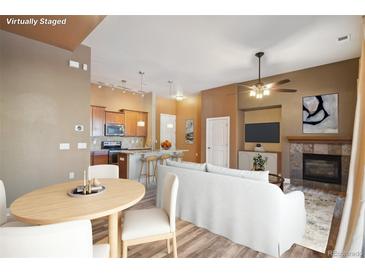 Open-concept living room showcases a fireplace, modern ceiling fan, and seamless flow into the kitchen at 305 Inverness Way # 102, Englewood, CO 80112