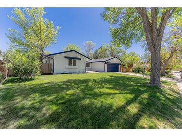 Well-maintained home with a green lawn and mature trees, showcasing curb appeal at 1486 S Kingston St, Aurora, CO 80012