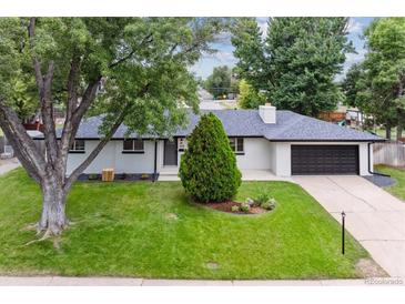 Charming single-story home with a manicured lawn, lush trees, and a modern dark-colored garage door at 210 E Graves Ave, Centennial, CO 80121