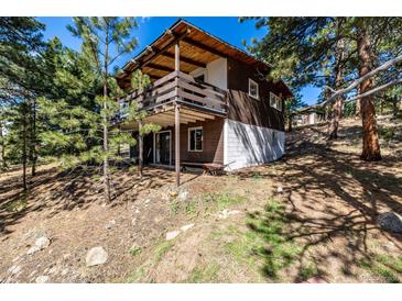 Charming cabin with a large wooden deck surrounded by trees and natural landscape at 7105 Flagstaff Rd, Boulder, CO 80302