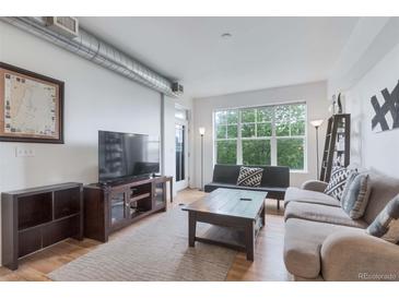 Bright living room with hardwood floors, modern furnishings and a large window overlooking the city at 1441 Central St # 209, Denver, CO 80211