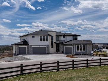 Beautiful modern home featuring stone accents, large windows, and a spacious three car driveway at 3226 Wingspan Pt, Castle Rock, CO 80108