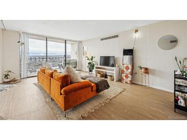 Inviting living room with balcony access, an orange sofa and ample natural light at 1020 15Th St # 35N, Denver, CO 80202