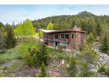 Stunning home with brick and stone exterior, surrounded by lush greenery and mature trees on a large lot at 401 Highway 72, Golden, CO 80403