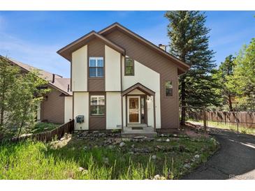 Charming two-story home with brown and white painted exterior, surrounded by green foliage and a quaint fence at 27124 Sun Ridge Dr, Evergreen, CO 80439