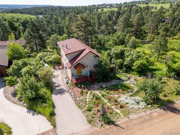 Charming two-story home with colorful front porch and beautiful landscaping in a lush, wooded setting at 347 Buena Vista Ave, Palmer Lake, CO 80133