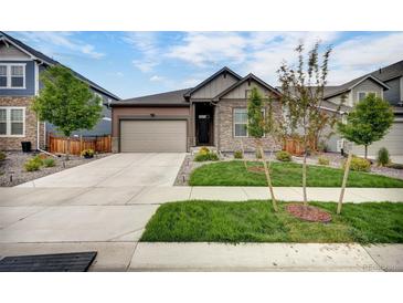 Charming single-Gathering home showcasing a landscaped front yard, stone accents, and a two-car garage at 5771 Slate River Pl, Brighton, CO 80601