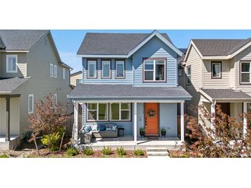 Charming two-story home showcasing a covered front porch with stylish seating and an eye-catching orange front door at 9768 E 62Nd Dr, Denver, CO 80238