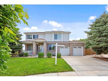 Charming two-story home featuring a brick facade, well-manicured lawn, and attached two-car garage at 11821 Joplin Ct, Commerce City, CO 80022