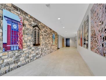 Long hallway featuring stone accent wall and modern art at 1044 Rockhurst Dr # 202, Highlands Ranch, CO 80129