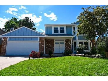 Inviting two-story home with a well-manicured lawn and a charming blue and brick facade at 4753 S Gar Way, Littleton, CO 80123
